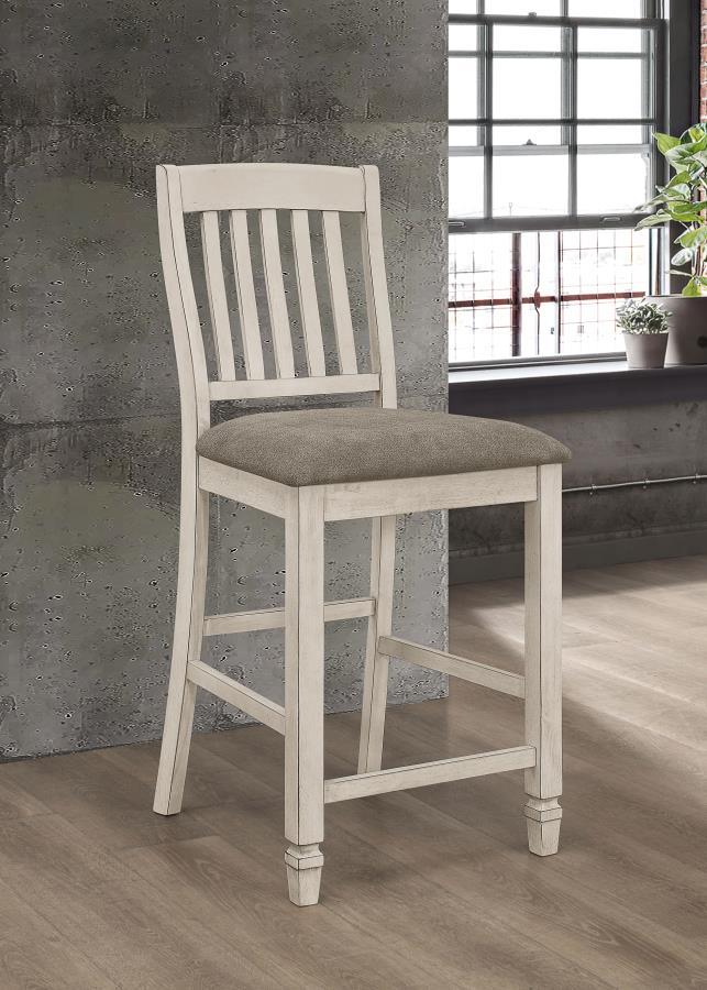 Give your dining space a charming, farmhouse inspired update. This wooden, counter height stool blends a rustic cream finish with a soft, upholstered seat to create a truly inviting design. Thick, plush padding makes it ultra-cozy and comfortable. A slat 
