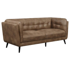 Elevate your mid-century modern living room seating area with this contemporary Chesterfield shelter style sofa, upholstered in a soft and smooth brown microfiber leather throughout its welt-trimmed and grid tufted seats and cushions. Plush and inviting w