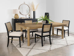 This dining set blends modern craftsmanship with natural textures for a refined yet inviting feel. The dining table features a trestle base with an antique brass-finished metal stretcher bar, adding stability and contrast. Rounded corners soften the recta