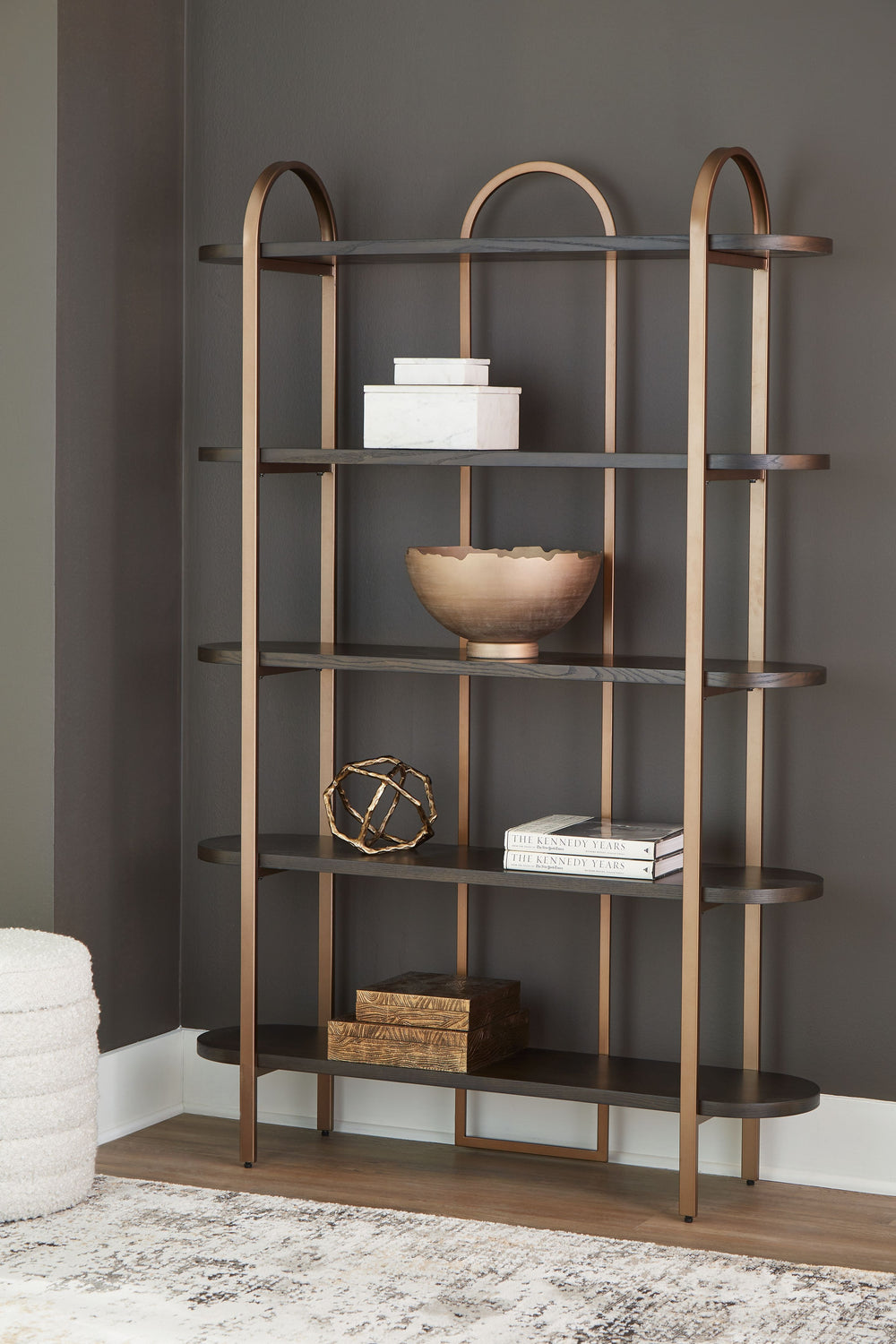 With its mixed-material look, this bookcase seamlessly fits into a wide range of modern settings. Five fixed display shelves in a dark brown finish are balanced by sleek antiqued goldtone metal supports. Offering storage and superior style for books or sh