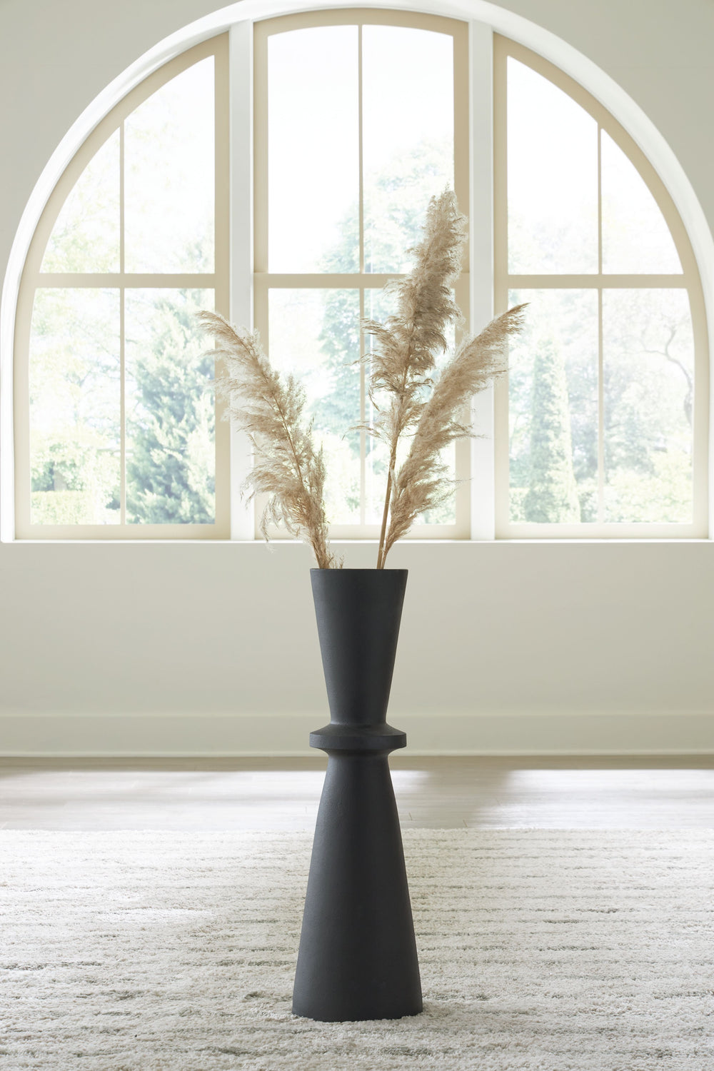 Crafted with contemporary spaces in mind, this black-hued vase is a versatile addition to your decor. Its hourglass shape and textured pattern make for an eye-catching standalone piece. Chic in an office corner or greeting guests in the entryway, this vas