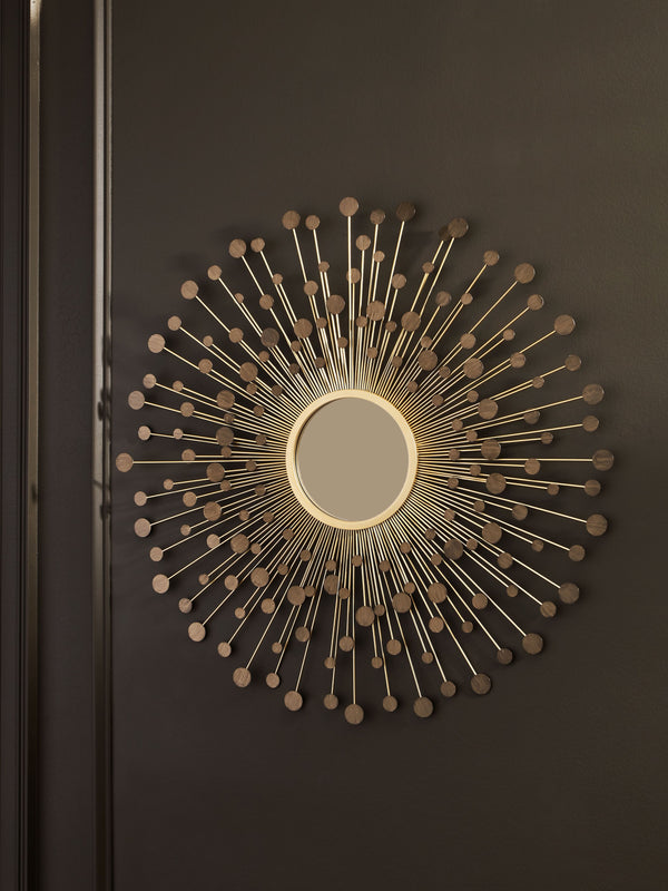  this accent mirror is a trendy take on wall decor. Its metallic spokes splay outward to create a sculpture-like frame. With goldtone and bronze-tone finishes