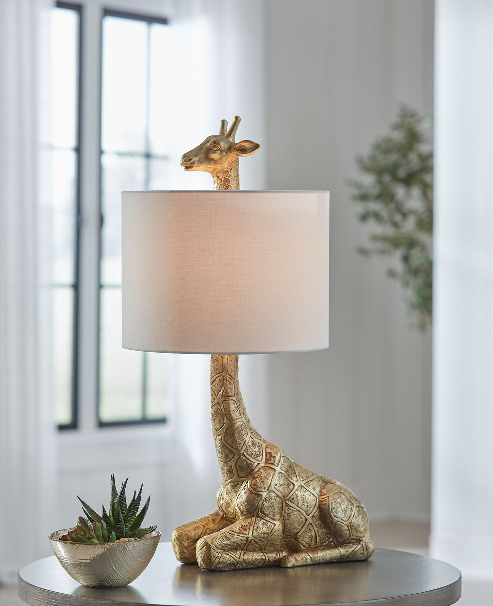This giraffe lamp combines contemporary style with eclectic charm. The curious animal peeks out over the top of the shade, adding a playful touch to the safari-inspired vibe. For glam appeal, a goldtone finish completes the look.<br><br><b>Additional Dime