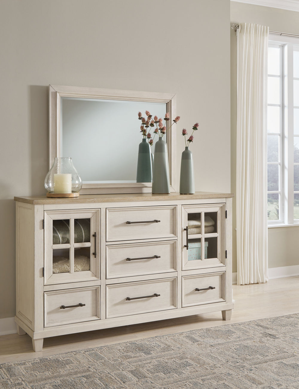 This dresser and mirror set elevates the art of modern farmhouse design. Its two-tone aesthetic blends antiqued white and light grayish brown for a charming finish. Framed drawer fronts and windowpane cabinets lend a country feel. Conveying a feeling of r