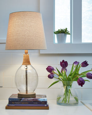 This elegant table lamp adds a timeless touch to coastal interiors. Featuring a seeded glass jar-style body with rope accents, it-'s the perfect piece for your bedside nightstand or living room side table. A metal circular platform base and modified drum 