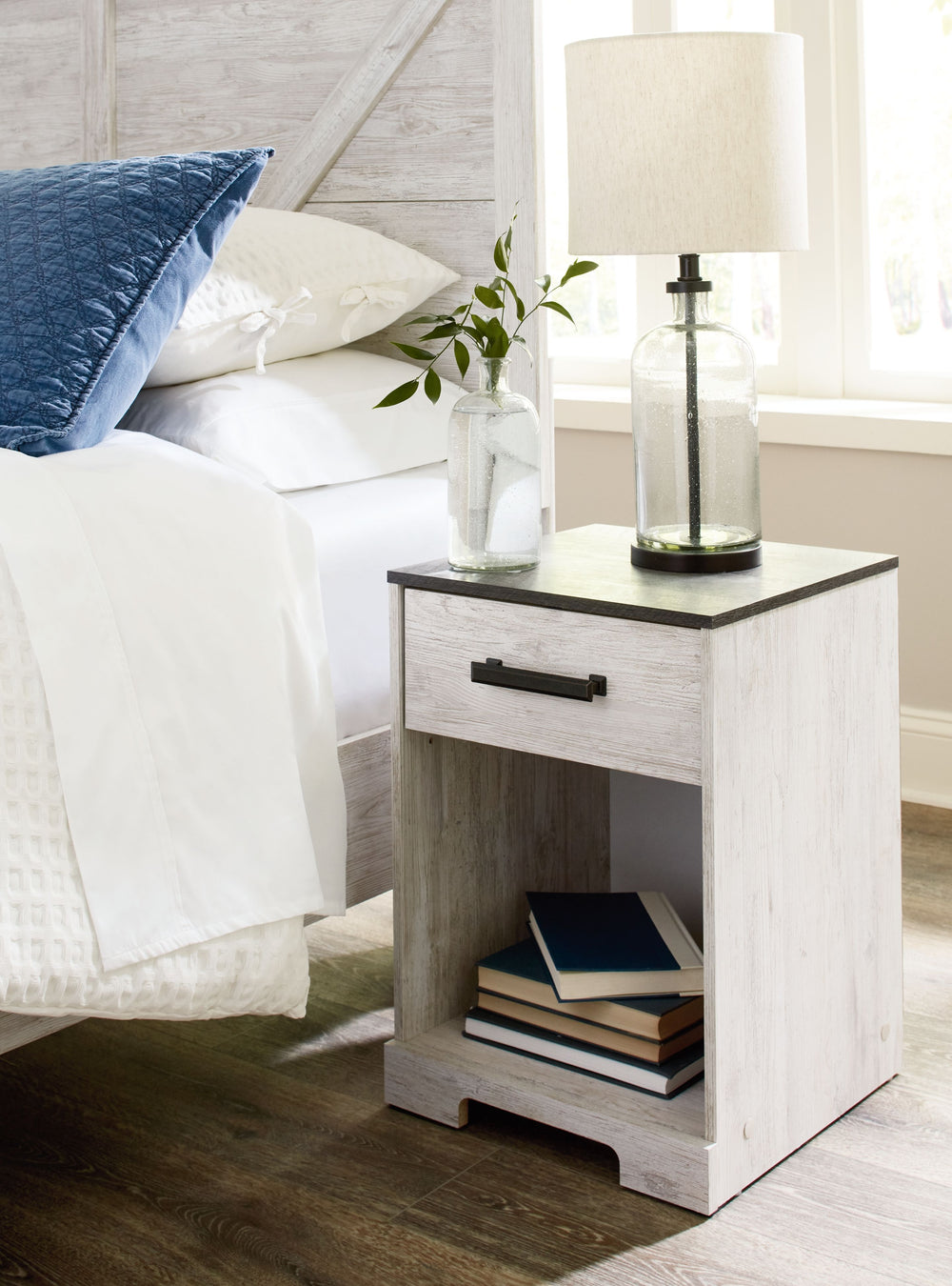Give provincial a new meaning with the chic look of this nightstand. A two-tone finish keeps this piece light and fresh, while the warm pewter-tone hardware adds an industrial touch. The open cubby provides display space or accommodates a storage bin to a