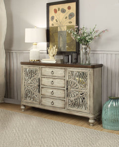 The elegant Vernon Console Table features an antique white finish with decorative cabinet door inlays. The rectangular wood console table features 4 center drawers and 2 doors on each end that reveal 4 additional shelves, providing ample display and addit