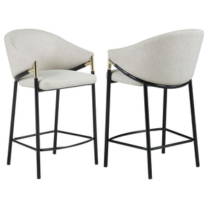 This pair of two stools offer a Hollywood regency look. With a tall and sleek design, the legs come in a glossy black finish that lends to many color palettes and offers a handsome look. Each stool has a cushioned seat, wrapped in a linen-like fabric that