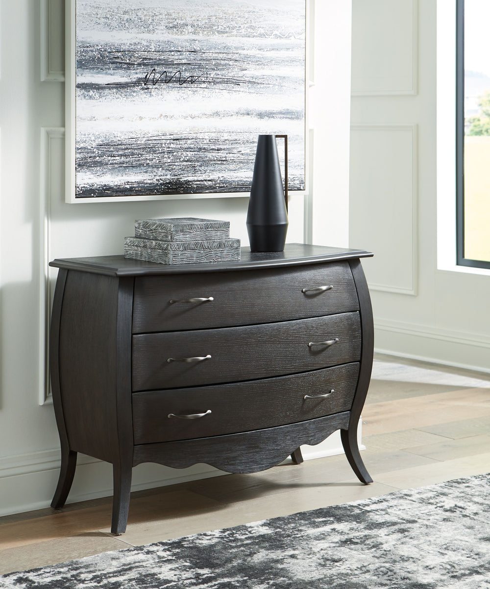 Beautiful curving lines and charming vintage flair give this cabinet its elegant antique feel. The dark finish is accented with silvertone drawer pulls, while three drawers ensure a smooth motion for your storage needs. What a charming complement to your 