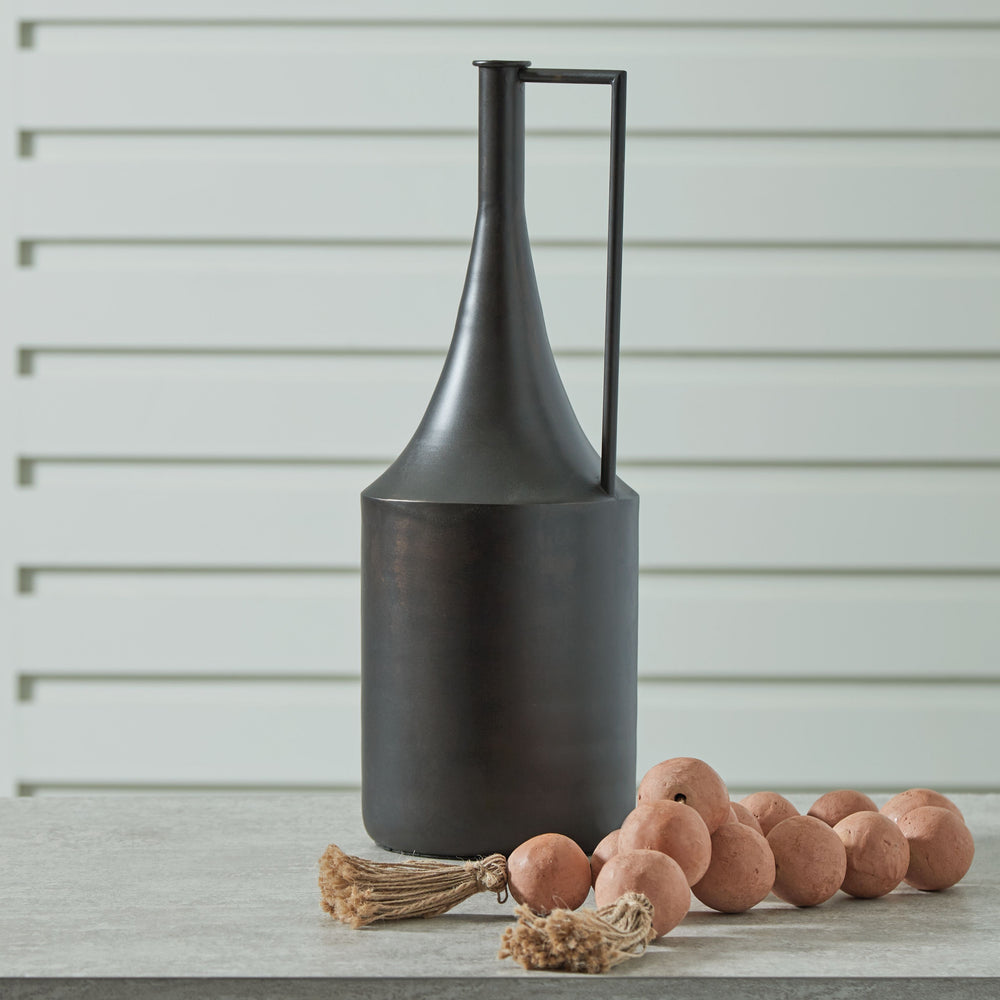 Chic on a tabletop or shelf, this vase is an eye-catching accent. Its angular handle provides a sharp, stunning geometric contrast to the curved neck. Finished in a distressed brown hue, this piece plays well in spaces ranging from casual to contemporary.