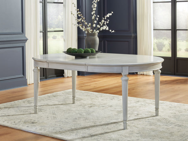  its classic antiqued white finish is paired with reeded legs and a tabletop with a butterfly-matched veneer pattern. With the removable center le