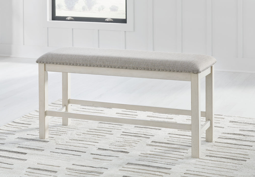 This counter height dining bench is sure to impress come mealtime. With its white finish and light gray upholstery, farmhouse-style seating has never been so fashionable. All thatâ€™s missing is you and your family.<br/><br/><b>Product Features</b><ul><li