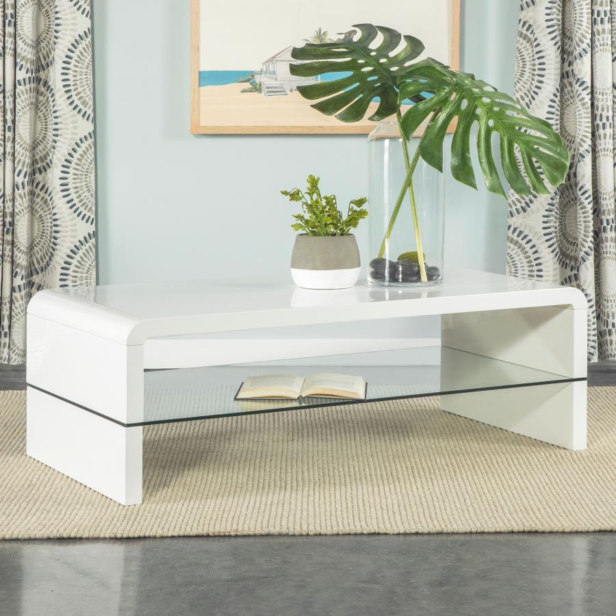 This ultra-modern coffee table showcases a sleek, high-gloss white finish and clean lines. Its rectangular tabletop flows seamlessly into waterfall edges, creating a contemporary silhouette. A clear tempered glass shelf offers an airy, open feel while pro
