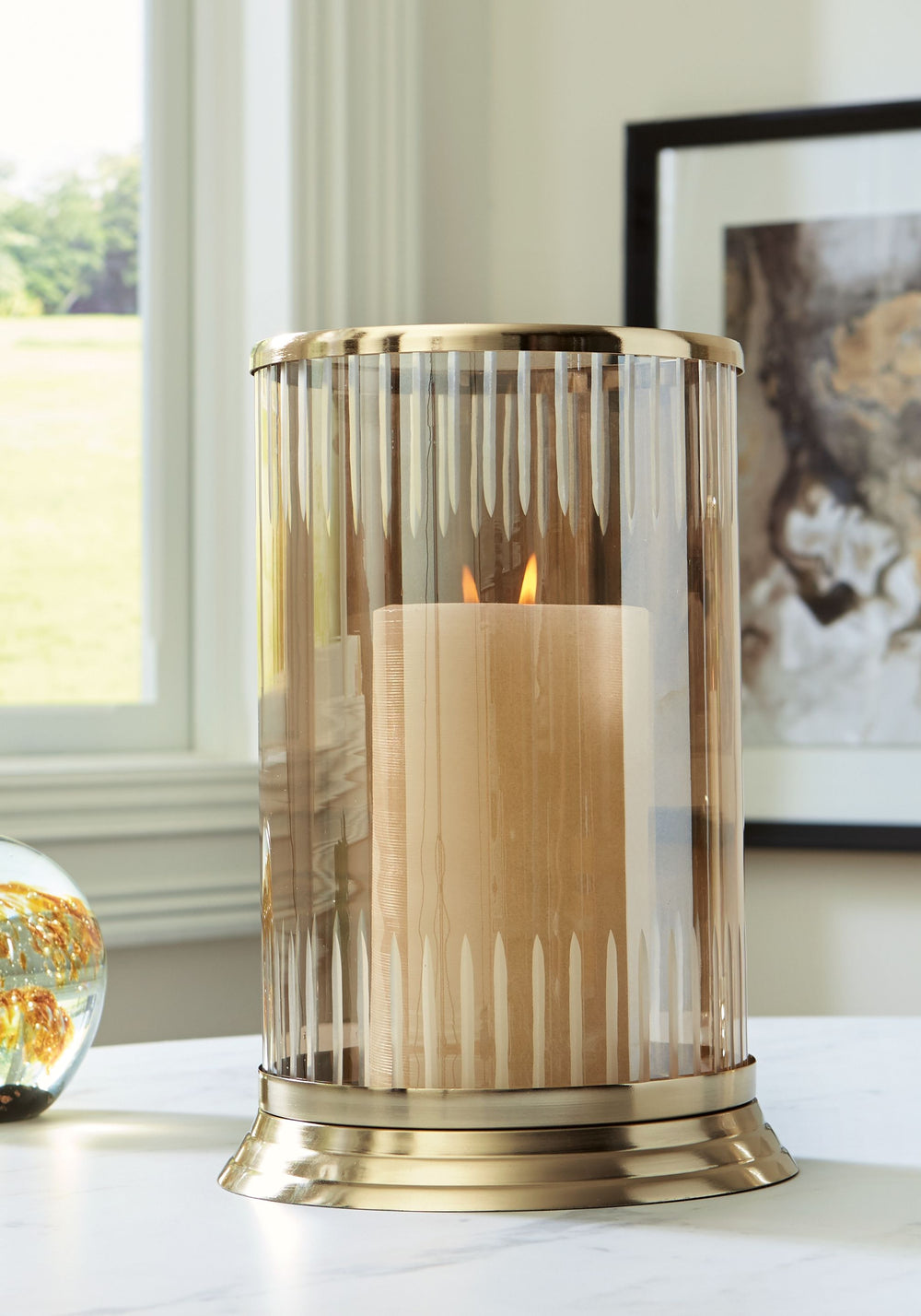 Illuminate your home in traditional style. A brass-tone finish on this candle holder brings a classic feel to the metal base. Its carved glass, in a light amber hue, gives you a timeless aesthetic you can love.<br/><br/><b>Product Features</b><ul><li>Made