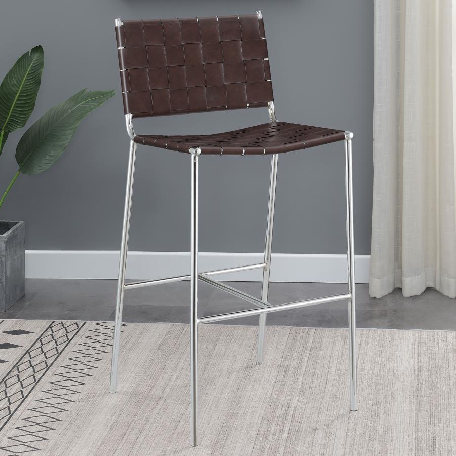 Mid-century elements lead the design aesthetic of this contemporary stool. A slim metal frame in a gleaming chrome finish offers a striking contrast against the brown faux leather accents. Narrow leatherette bands weave together to create a backrest and s