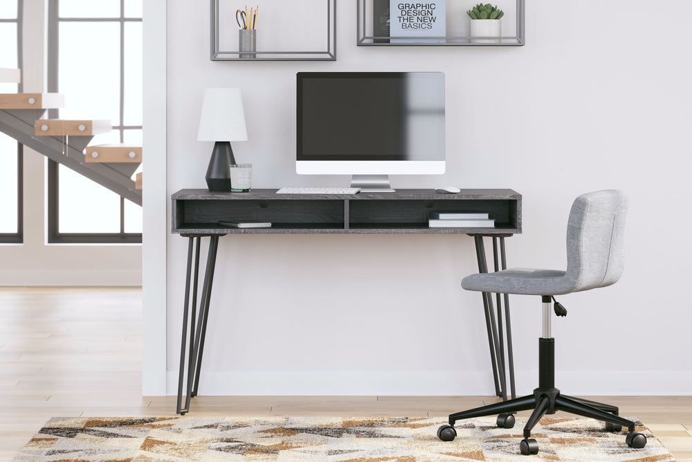 Sporting a sleek and simple profile, this home office desk is casual contemporary at its finest. The desktop is wrapped in a replicated dark charcoal gray wood grain and paired with decidedly mid-century style black legs for a familiar-yet-fresh design. A