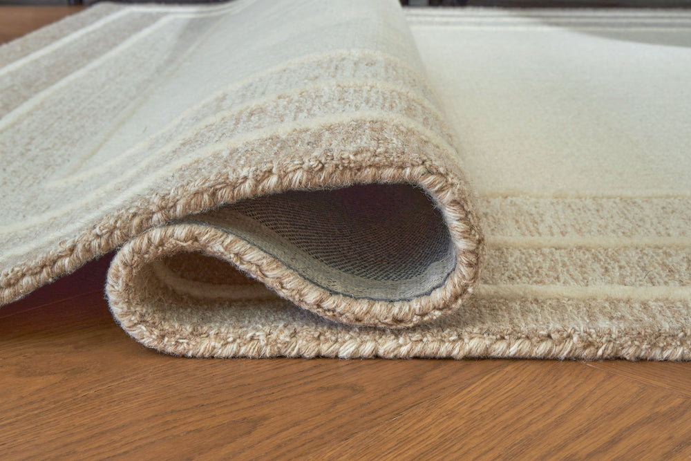 With its simple border design and soft, neutral color palette, this hand-tufted rug brings a touch of casual elegance to your abode. Its plush wool pile feels luxuriously soft underfootâ€”perfect for adding warmth and texture to your entertainment area, b