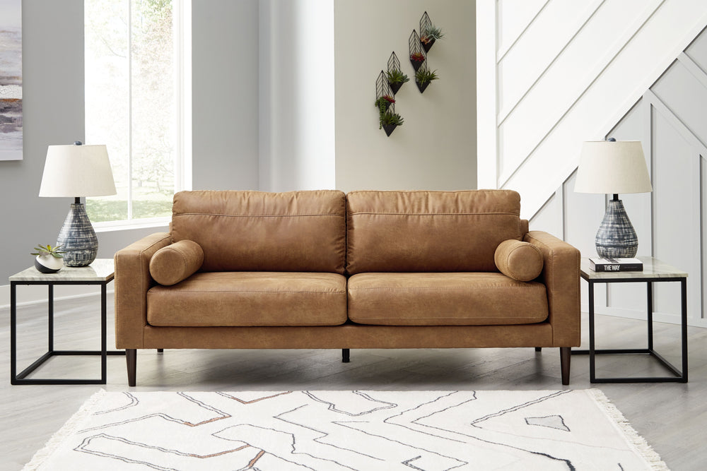 Small-scale style, tailored to perfection. This sofa echoes retro aesthetics with warm caramel faux leather, while its ultra-linear silhouette incorporates a contemporary edge. Versatile in form and function, the seat suits styles from modern boho to tran