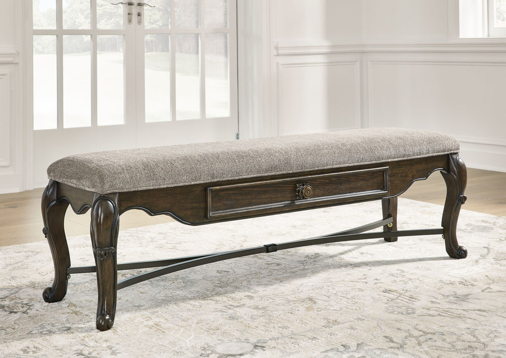 From its ornamental appliques to its large scale, this dining bench makes a bold statement. With ornately shaped legs, a plush cushioned seat and a storage drawer, the opulent bench wows with stunning style. The look is timeless. The feel? Right at home.<