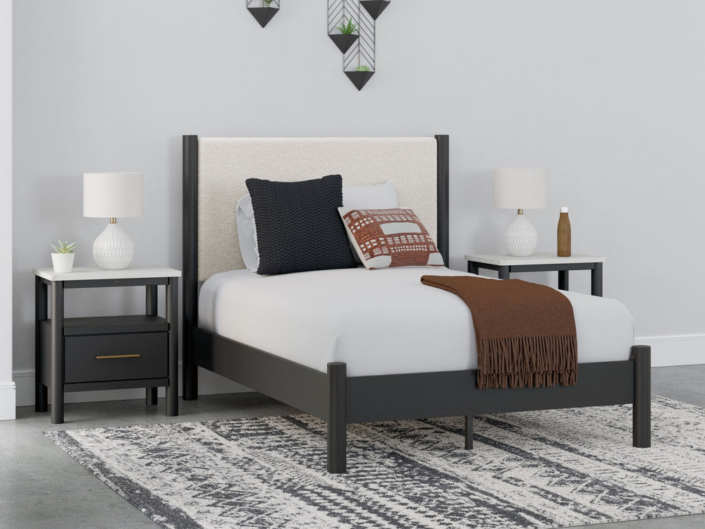 This full upholstered panel bed reflects your sophisticated approach to boho style. Crafted with both form and function in mind, its fresh white fabric beautifully contrasts the matte black finish. The versatile design suits all-neutral spaces or blends w