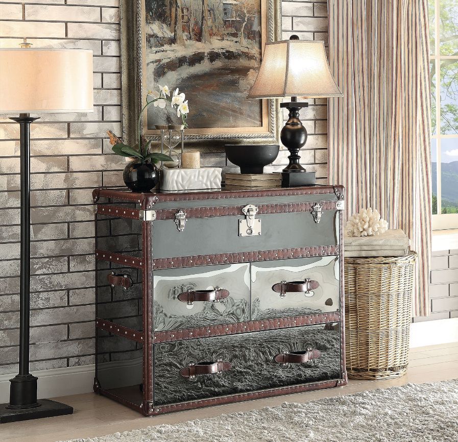 The Aberdeen collection combines different materials to bring an undeniable sensation to any living room. This sofa table features a trunk like design with stainless steel top and side panels, vintage dark brown top leather trim edging, single leather han