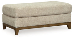 Serene style with a modern sensibility. Delight in the cozy, versatile embrace of this ottoman. It takes an on-trend approach to irresistible texture and natural beauty, showcasing soft upholstery accented with a transitional wood trim. As refined as it i