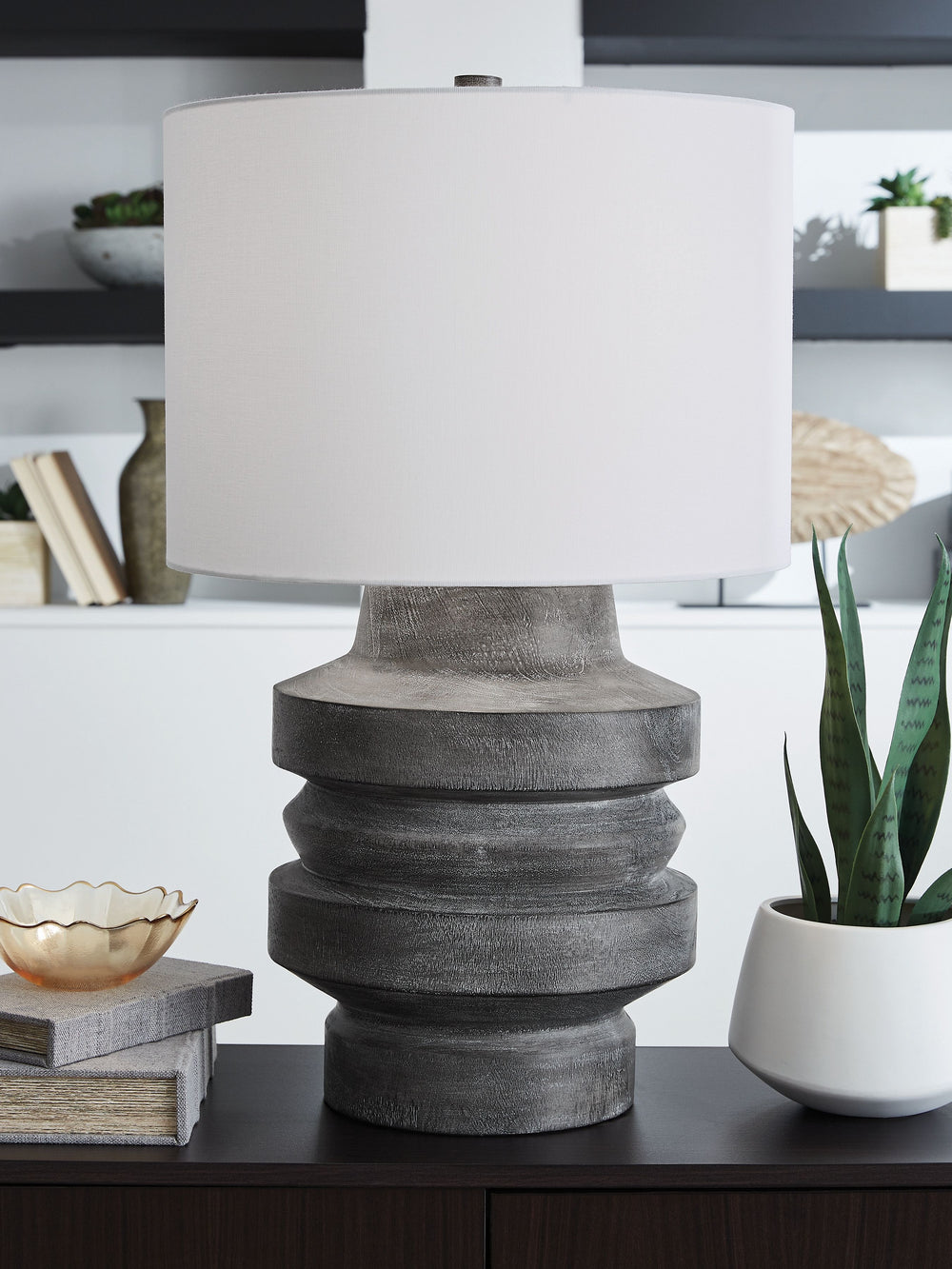 With this table lamp, you-'ll find an expert balance of modern design and casual function. Its distressed black faux wood finish captures the essence of natural motifs while maintaining a curated sense of character. What an artistic approach to everyday i