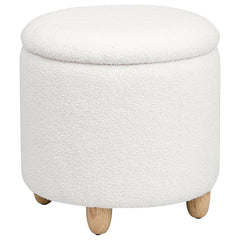 Nestled atop subtle, natural brown rounded wood feet, this round storage ottoman is a stylish statement of comfort and practicality. Upholstered in a soft faux sheepskin, it beckons with tactile appeal, inviting a moment of relaxation. The removable top u