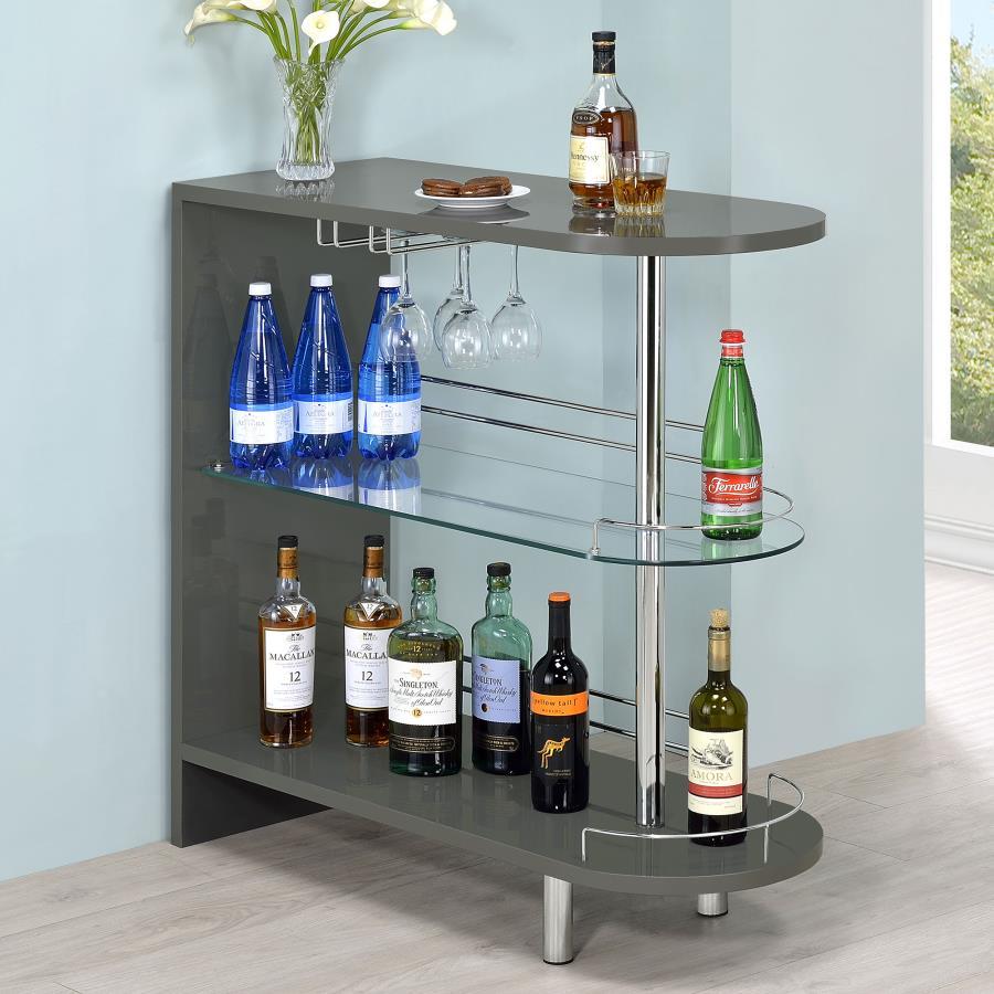 Add a fun retro feel to a modern living area with this contemporary bar table. In a glossy grey finish, the silhouette is cool and neutral. Tempered glass storage shelves offer a clean and open feel while displaying libation bottles in style. Included gua