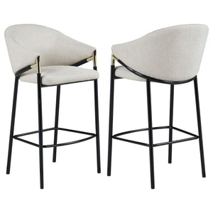 This pair of two stools offer a Hollywood regency look. With a tall and sleek design, the legs come in a glossy black finish that lends to many color palettes and offers a handsome look. Each stool has a cushioned seat, wrapped in a linen-like fabric that