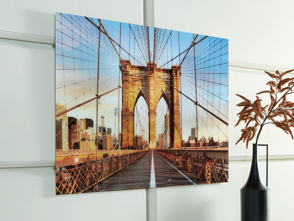 Bring a touch of iconic architecture to your home with this wall art. Captured in beautiful detail, the print on glass showcases the Brooklyn Bridge-'s majestic arches and intricate cables, set against the backdrop of a vibrant city skyline. This captivat