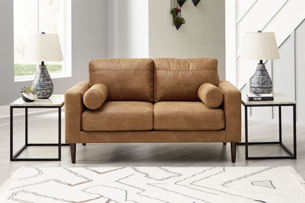 Small-scale style, tailored to perfection. This loveseat echoes retro aesthetics with warm caramel faux leather, while its ultra-linear silhouette incorporates a contemporary edge. Versatile in form and function, the seat suits styles from modern boho to 