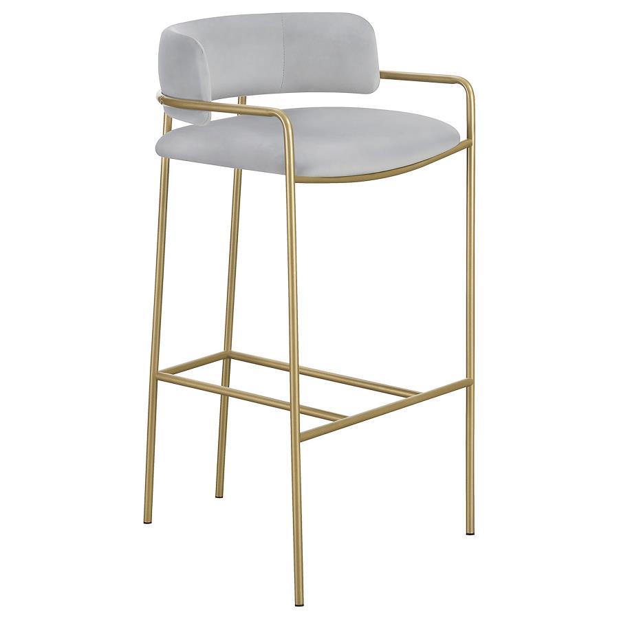 A soft and supple grey velvet envelops the comfy padded seat and linear backrest of this chic and glamorous stool. Situated and supported by a slim rod-like frame in a gold finish, this stool offers an air of sophistication to any bar top or kitchen islan