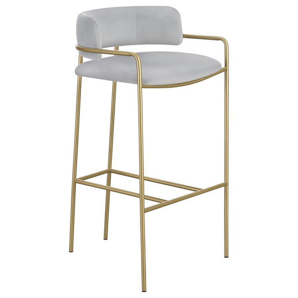 A soft and supple grey velvet envelops the comfy padded seat and linear backrest of this chic and glamorous stool. Situated and supported by a slim rod-like frame in a gold finish, this stool offers an air of sophistication to any bar top or kitchen islan