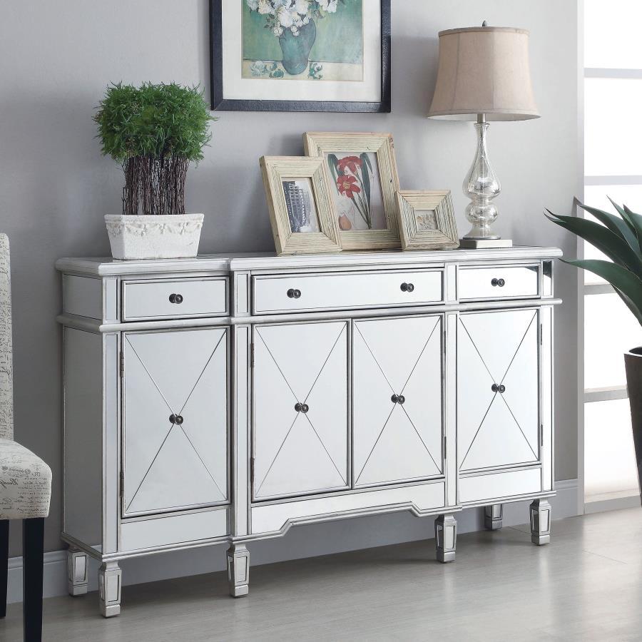 This accent cabinet offers a striking mix of function and glamour with its mirrored surface and silver finish. Framed in engineered wood, the cabinet features four doors with beveled mirrored panels and three top drawers for added storage. Inside, fixed s