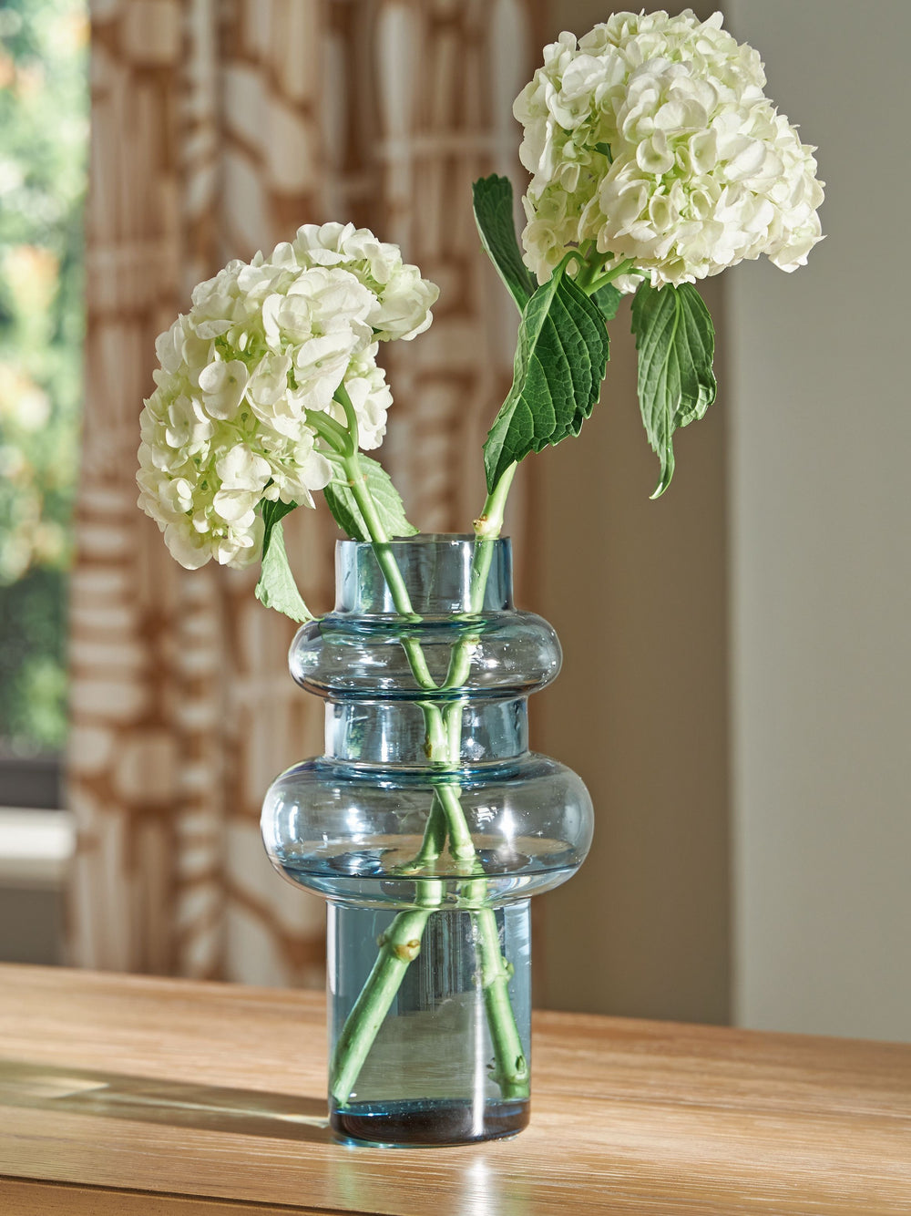 This contemporary vase is anything but ordinary. Displayed on its own or with faux greenery, the statement-making accentâ€”crafted from blown glass in a blue hueâ€”rounds out your modern decor beautifully.<br/><br/><b>Product Features</b><ul><li>Made of b