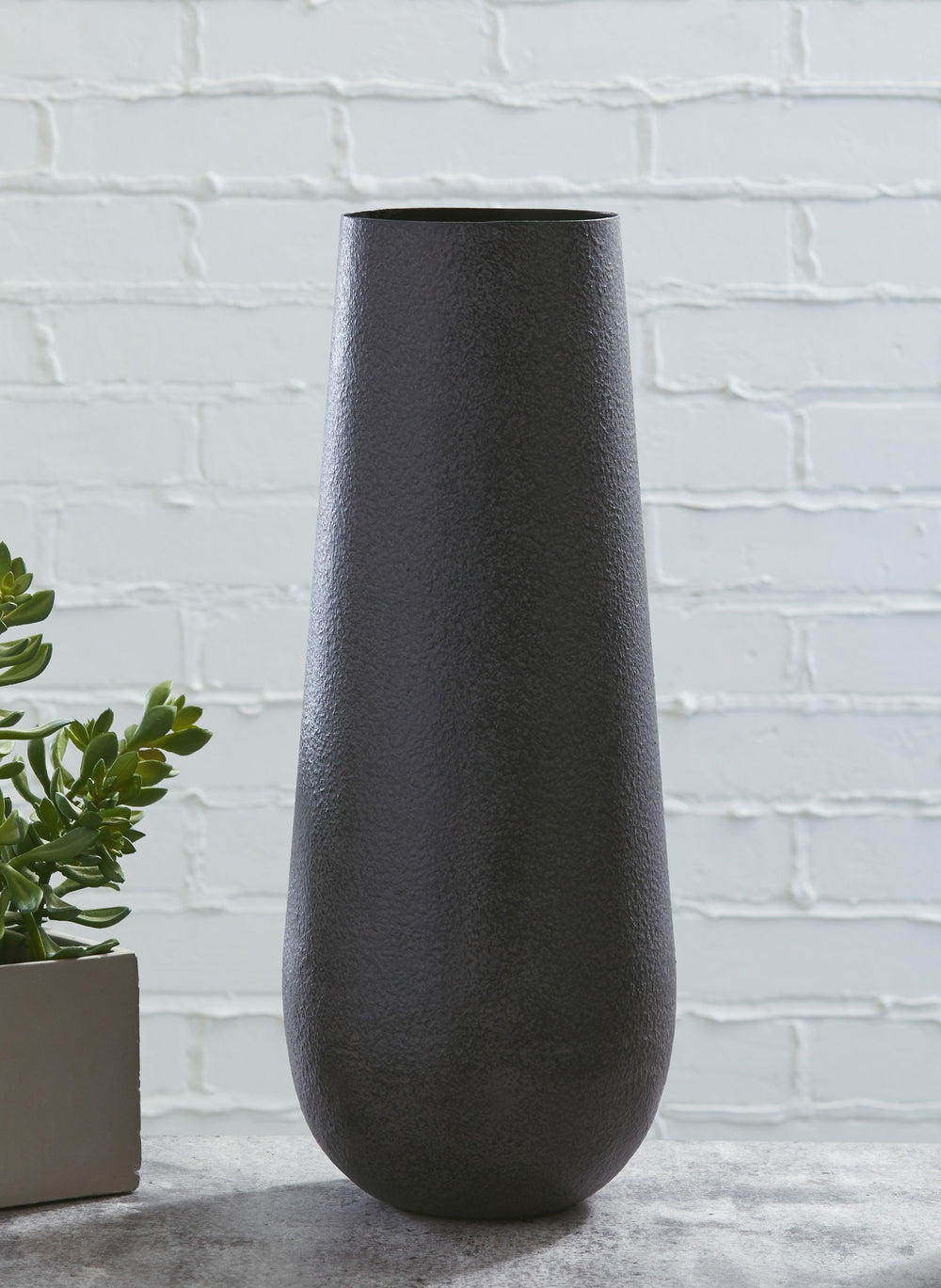 For those with an artful eye and a love of casual elegance, this metal vase is a beauty to behold. A cylindrical silhouette makes this striking home accent all the more alluring.<br/><br/><b>Product Features</b><ul><li>Made of metal</li><li>Antiqued brown
