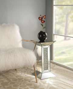 The gorgeous Nysa mirrored pedestal stand is a great addition to your foyer or living room. This table is a sight with its rectangular mirror top with a unique geometric base that is a combination of regular mirror and black decorative crystal center. Uni