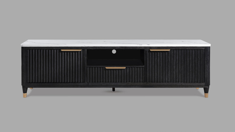 This entertainment console brings modern luxury and sleek sophistication to any living space. Featuring a striking contrast of a black, fluted wood facade with a pristine white faux marble top, this piece embodies refined elegance. Brass-tone accents and 