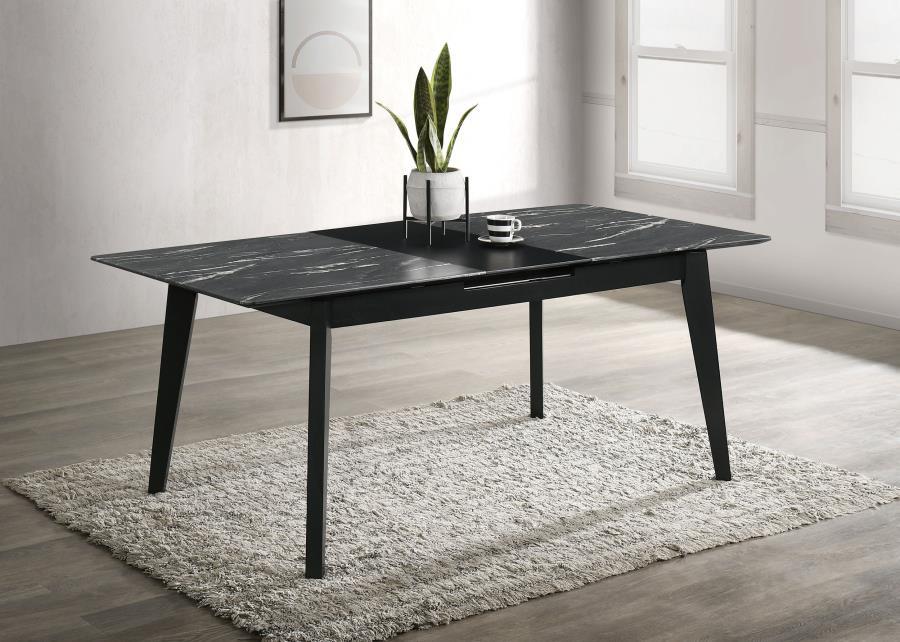 The luxurious look of faux marble creates a glam sensibility for a modern dining table. The black marble look of the tabletop complements a sleek base with fin-style legs and a recessed apron. The table includes a self-storing leaf for easy expansion to a