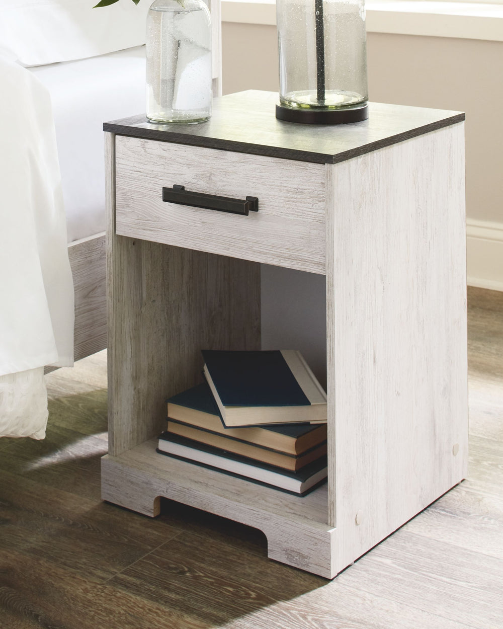 Give provincial a new meaning with the chic look of this nightstand. The two-tone finish keeps this piece light and fresh while the warm pewter-tone hardware adds an industrial touch. The open cubby provides display space or accommodates a storage bin to 