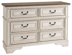 Elevating the art of traditional cottage styling, this dresser is your dream bedroom retreat realized. Its antiqued two-tone aesthetic blends a chipped white with a distressed wood finished top for added charm. Framed drawer fronts and decorative corbels 