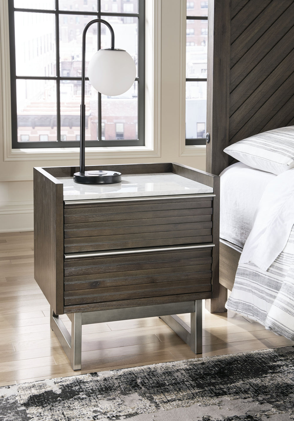 Clean lines lend sophistication and structure to this nightstand. Its complex rich grayish brown finish contrasts perfectly with a white marble top, while the streamlined silhouette features overlay slats to create visual interest. A metal base and bar pu
