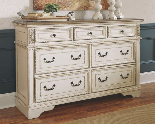Elevating the art of traditional cottage styling, this dresser is your dream bedroom retreat realized. Its antiqued two-tone aesthetic blends a chipped white with a distressed wood finished top for added charm. Framed drawer fronts and decorative corbels 