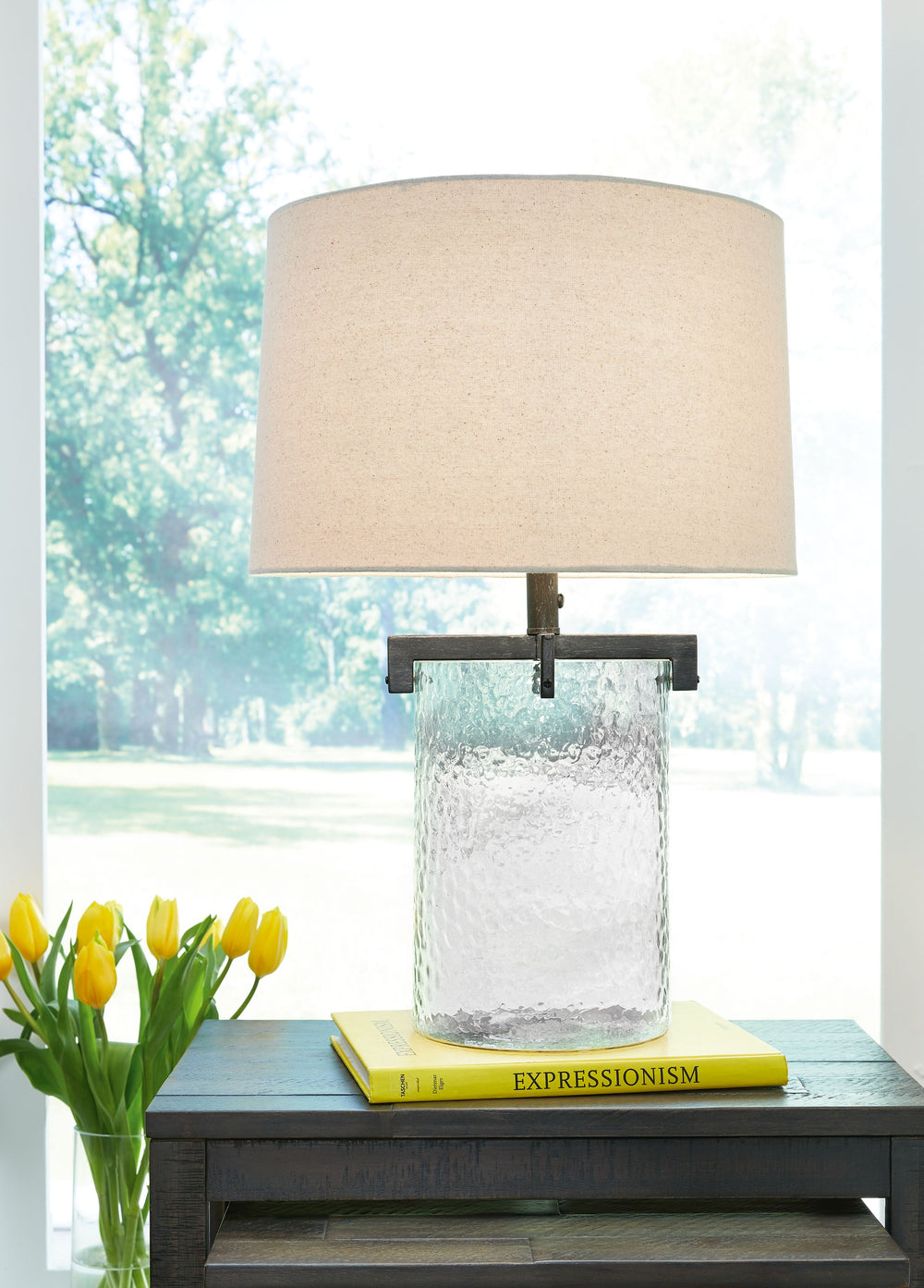 Inspired by master glass artisans, this unique table lamp is designed to highlight its quality materials. Crafted with clear, artistically textured glass with classic antiqued black metal detailing, this stunning lamp adds an elegant touch to any room.<br