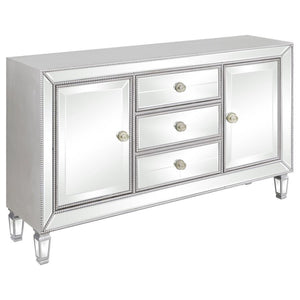 Make a glamorous statement with this champagne-finished accent cabinet, featuring dazzling mirrored panels and elegant beaded trim. Designed with three center drawers and two side doors, it offers ample concealed storage without sacrificing style. Tapered