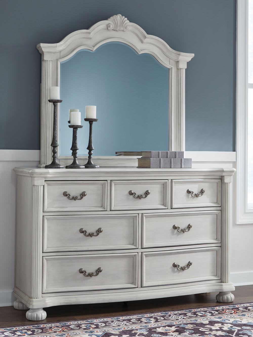 Transform your inner sanctum into a haven of timeless elegance and functionality. This traditionally styled dresser with mirror is adorned in a classic antiqued white finish, highlighted by a serpentine-shaped front with thick decorative moulding. Its dra