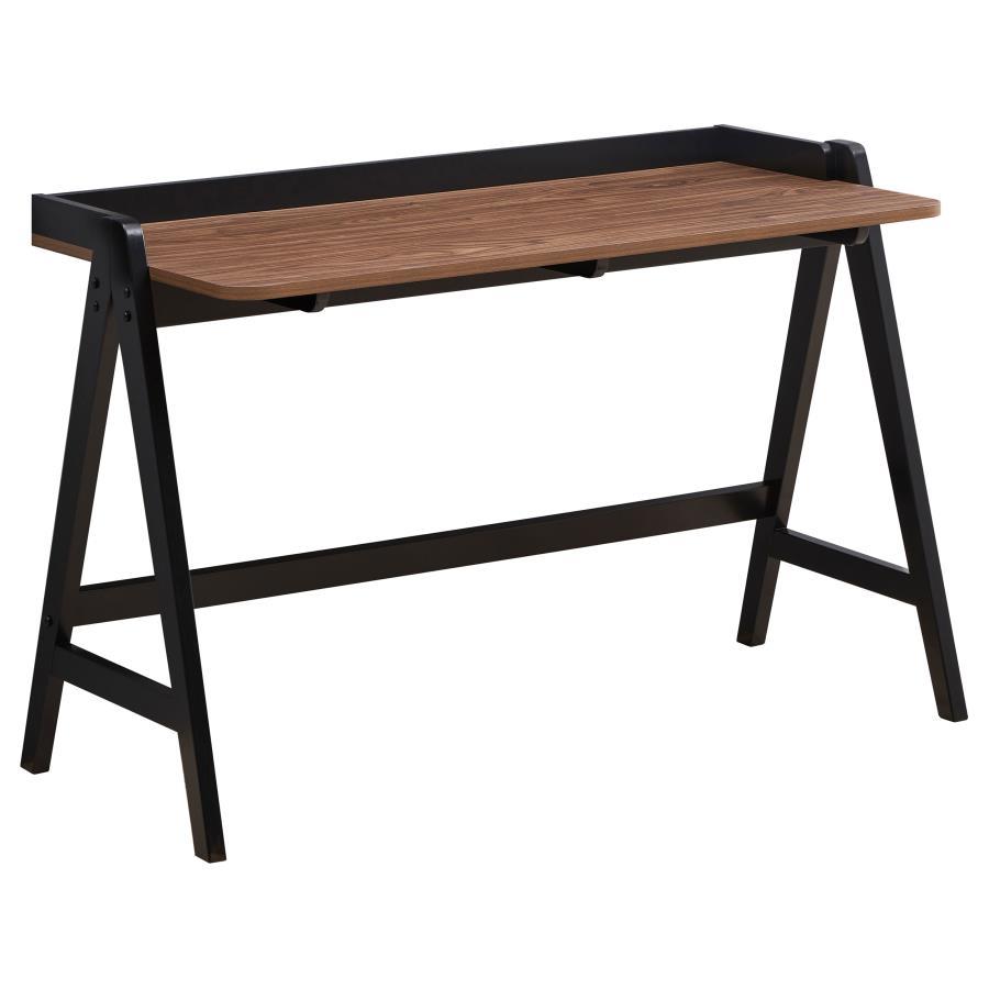 A modern take on a trestle-style drafting table, this industrial style writing desk offers a minimal aesthetic to a home office space. A black trestle base in an A-frame design supports a clean tabletop surface in a rich walnut finish, lending a colorful 