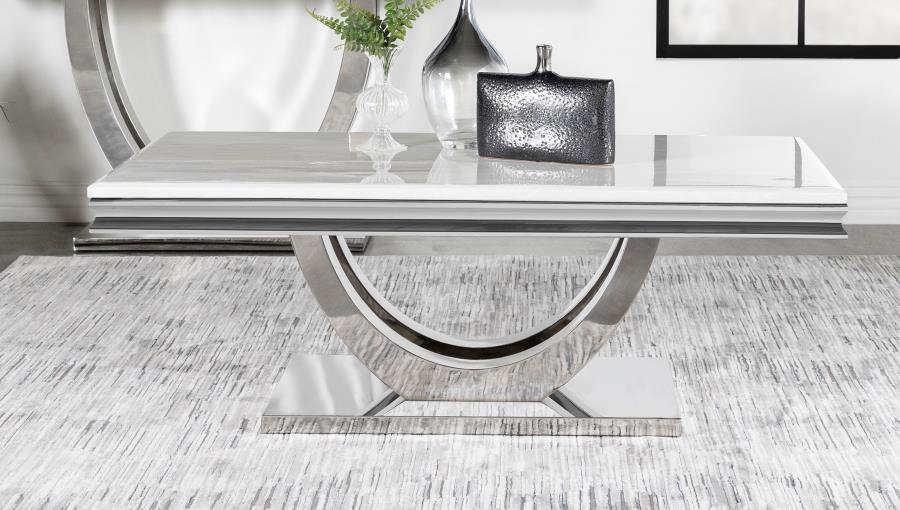 This coffee table showcases modern glam with a sintered stone top, featuring a marble-like appearance and beveled edges. Its sweeping demilune pedestal base, crafted from polished stainless steel, combines sculptural elegance with durable construction. Th
