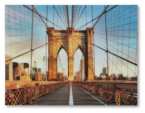 Bring a touch of iconic architecture to your home with this wall art. Captured in beautiful detail, the print on glass showcases the Brooklyn Bridge-'s majestic arches and intricate cables, set against the backdrop of a vibrant city skyline. This captivat